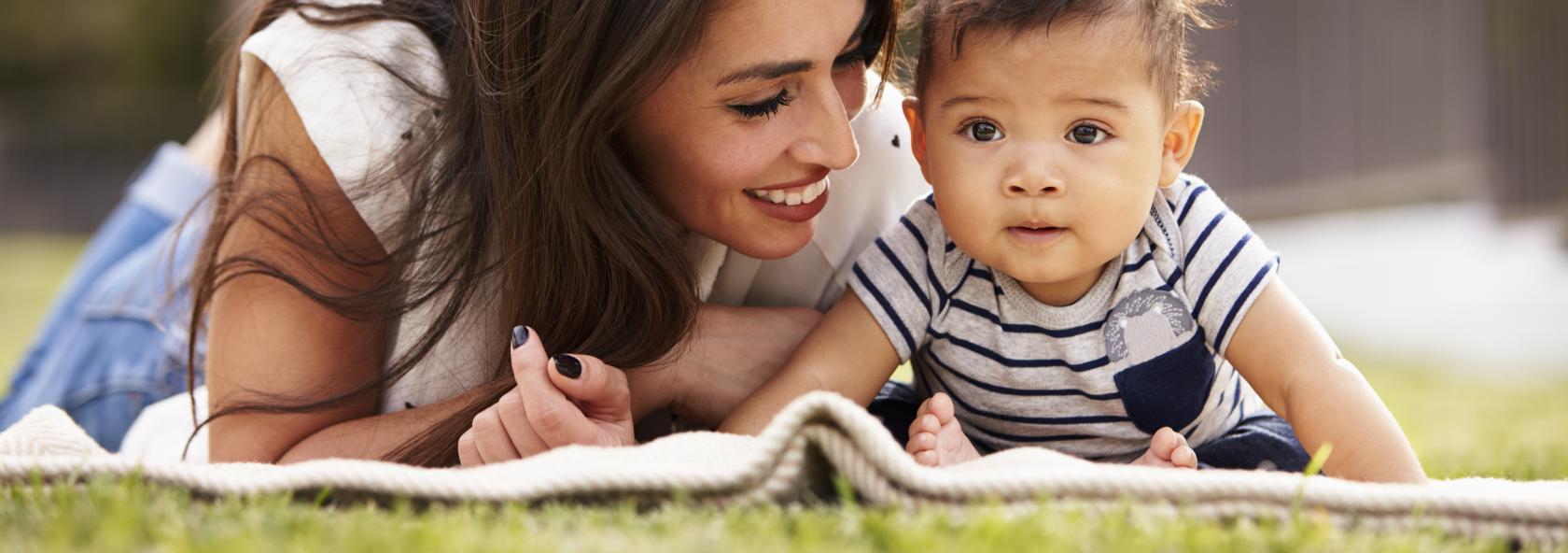 Mother and child laying on a blanket outside